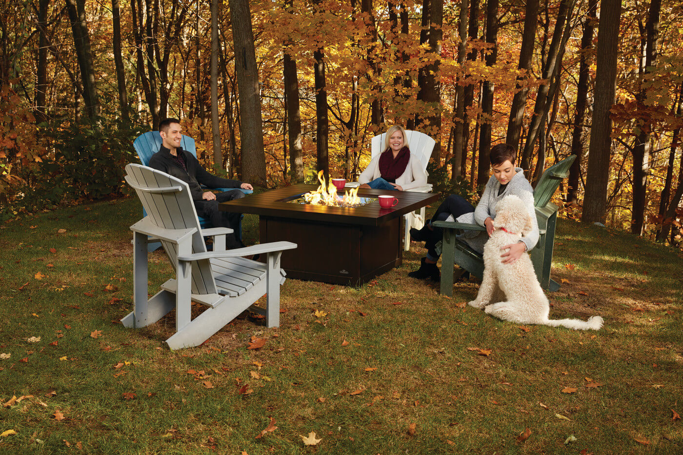 Friends gathered around a linear gas fire table at night
